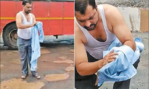 குண்டும், குழியுமான சாலையில் துணி துவைத்த வாலிபர்