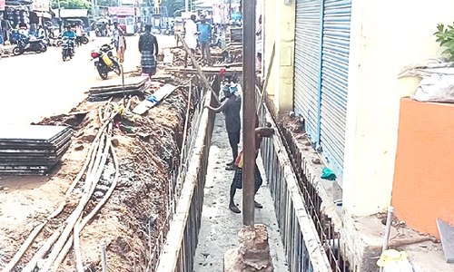 சாக்கடை கால்வாய் நடுவே மின்கம்பம்