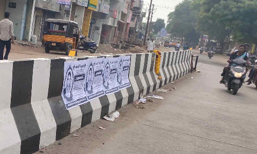 சாலையின் தடுப்பு சுவரில் சுவரொட்டிகள்