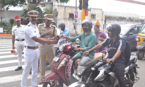 ஹெல்மெட் அணிந்த இருசக்கர வாகன ஓட்டிகளுக்கு இனிப்பு- பூங்கொத்து: போக்குவரத்து போலீசார் வழங்கினர்
