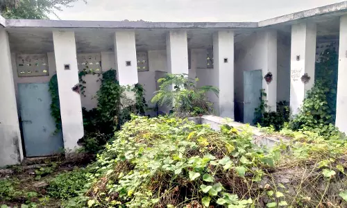 புதர்மண்டி பாழடைந்து காணப்படும் பொது கழிப்பறை கட்டிடம்