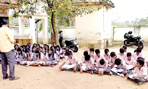 மரத்தடியில் படிக்கும் துவரங்குறிச்சி அரசு பள்ளி மாணவர்கள்