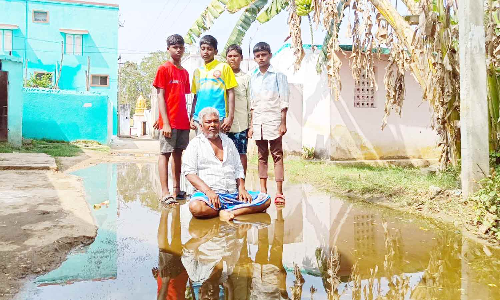 மழைநீரில் அமர்ந்து விவசாயி நூதன முறையில் போராட்டம்