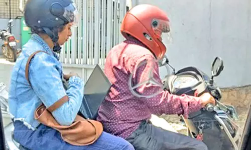 பைக் சவாரியின் போது லேப்-டாப்பில் வேலை பார்த்த பெண்: விவாதத்தை ஏற்படுத்திய புகைப்படம்