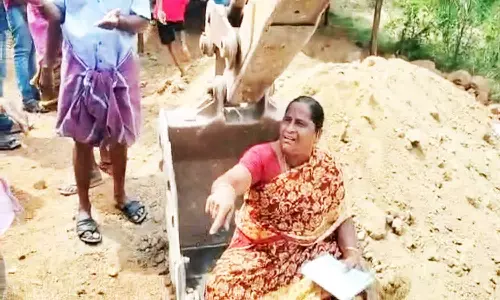 பொக்லைன் எந்திரம் மீது அமர்ந்து பெண் போராட்டம்