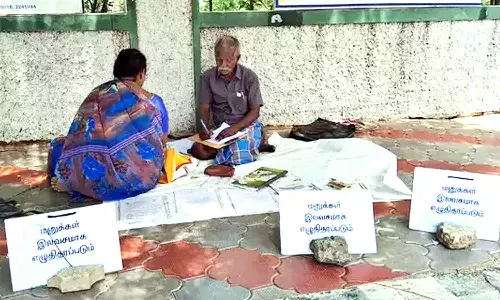 திருப்பூர் கலெக்டர் அலுவலகத்தில் பொதுமக்களுக்கு இலவசமாக மனு எழுதி கொடுக்கும் முதியவர்