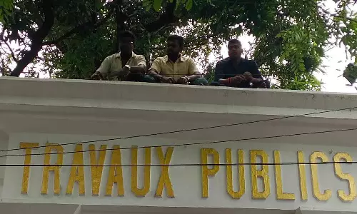 நுழைவு வாயில் மீது ஏறி பணி நீக்க ஊழியர்கள் போராட்டம்