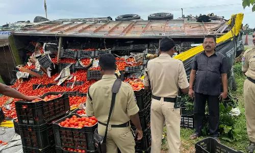 பொதுமக்கள் அள்ளி செல்ல முயற்சி- சாலையில் கவிழ்ந்த தக்காளி லாரிக்கு போலீஸ் பாதுகாப்பு
