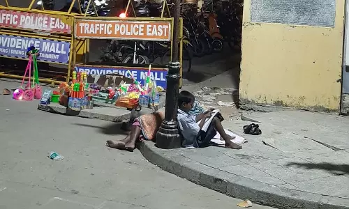 புதுவை கடற்கரை சாலையில் தெருவிளக்கு வெளிச்சத்தில் படிக்கும் சிறுவன்