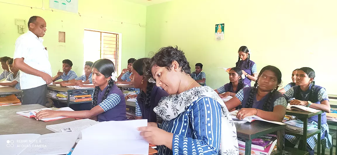 பாடம் நடத்தியதை மாணவிகளுடன் பெஞ்சில் அமர்ந்து கவனித்த கலெக்டர்