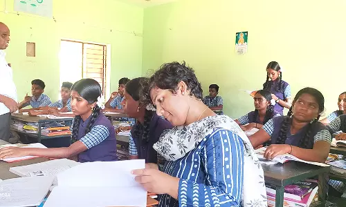 பாடம் நடத்தியதை மாணவிகளுடன் பெஞ்சில் அமர்ந்து கவனித்த கலெக்டர்