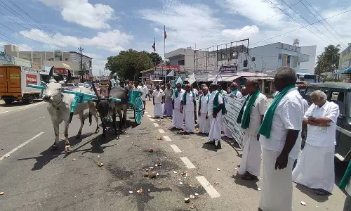 சூலூர் அருகே மாட்டு வண்டியில் ஊர்வலமாக வந்து தேங்காய் உடைத்து விவசாயிகள் போராட்டம்