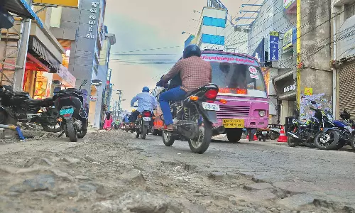 குண்டும், குழியுமாக காட்சியளிக்கும் மீனாட்சிபுரம்-கம்பளம் சாலை