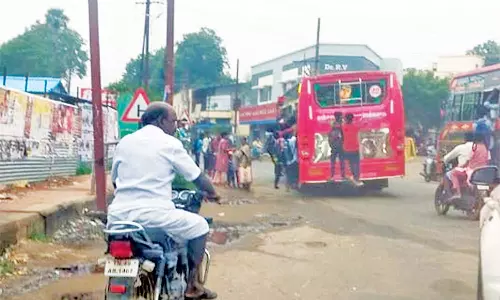 பஸ்சின் பின்புற ஏணியில் நின்றும், படிக்கட்டில் தொங்கியப்படியும் பயணம் செய்யும் மாணவர்கள்