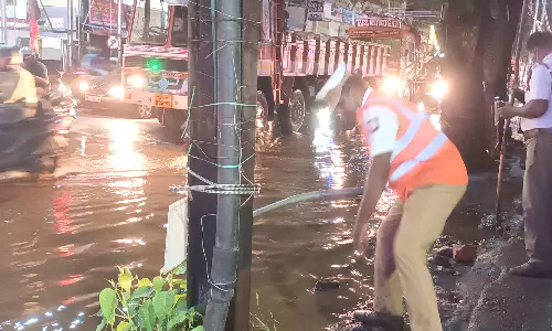 கோவையில் சாலையில் தேங்கிய மழைநீரை அகற்றிய போலீசார்