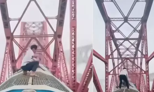 ஓடும் ரெயிலின் மேற்கூரையில் நின்று சாகசம் செய்த வாலிபர்- வீடியோ