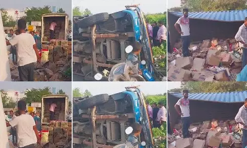 ஐதராபாத் அருகே லாரி கவிழ்ந்து விபத்து: பெட்டி பெட்டியாக மது பாட்டில்களை தூக்கி சென்ற பொதுமக்கள்