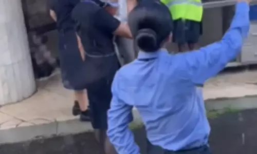 மழையில் இருந்து பயணிகளை பாதுகாத்த விமான ஊழியர்கள்