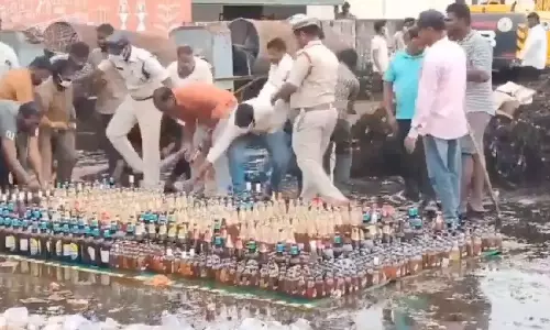 Andhra cops line up liquor bottles for disposal, locals grab and run off.