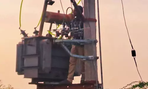 மின் கம்பத்தை அகற்றக்கோரி டிரான்ஸ்பார்மர் மீது ஏறி எதிர்ப்பு தெரிவித்த நெடுஞ்சாலைத்துறை அதிகாரி