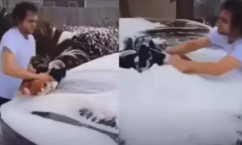 3 மாத குழந்தையை பயன்படுத்தி காரில் பனியை துடைத்த வாலிபர்