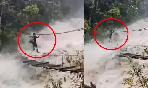 VIDEO: காட்டாற்று வெள்ளத்திற்கு நடுவே தொங்கு பாலத்தில் ஆற்றை ஆபத்தான முறையில் கடக்கும் நபர்