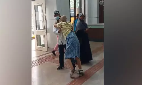 கோவை அரசு ஆஸ்பத்திரியில் வீல் சேர் வழங்காததால் முதியவரை இழுத்துச் சென்ற மகன்-  2 ஊழியர்கள் சஸ்பெண்டு